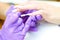 A manicurist paints his nails with white varnish