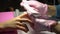 Manicurist in pink gloves polishes girl nails