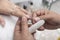 A manicurist places a clear nail extension to the finger. At a salon or parlor