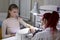 A manicurist puts a nail brush with a brush on the nails of a client of the salon.