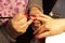 Manicurist putting black shellac on the fingernails of a lady client in a beauty salon with a small applicator. Master