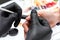 A manicurist removes cuticles during a nail extension procedure in a beauty salon. Professional hand care