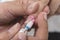 A manicurist uses an electric nail file to remove nail polish and the remnants of the acrylic. Nail extension removal at a salon