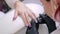 Manicurist woman in a beauty salon decorates client\'s nails with gel varnish with rhinestones