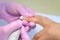 Manicurist woman removes shellac gel using manicure machine, hands closeup.