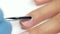 Manicurist works on the nail with a spatula and pushes back cuticles. Close up