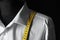 Mannequin with custom tailored shirt and measuring tape on dark background, closeup