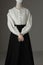 A mannequin with human hands dressed as a Victorian woman wearing a linen garibaldi blouse and black skirt