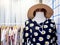 Mannequins wearing woman summer dress, floral shirt, sunglasses and straw hat near coat rack in dressing room