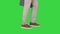 Mans feet is walking in jeans and sneakers on a Green Screen, Chroma Key.