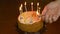 Mans hand with lighter fire candles on cake. Festive cake with burning candles on home table. Preparation for birthday