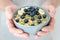 Mans hands hold a blue bowl with oatmeal, blueberry bananas and pumpkins seeds