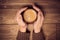 Mans hands holding a cup of coffee with foam over wooden table,