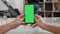 Mans point of view holding a smartphone vertically with green screen on