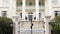 Mansion gates and green trees in summer against the background of the white house. Tilt up.