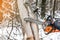 Manual chainsaw. Man hands, saws a tree in the woods in winter a