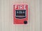 Manual fire alarm activation pull station on modern wooden wall - signage reading: â€œFIRE` and â€œPULL DOWNâ€.