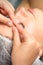 Manual sculpting face massage in the spa. Fingers of beautician make facial massage eyebrow of a young woman in