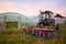 Manual seedling planter mounted to a tractor in front of greenhouses at sunset