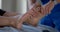 Manual therapist is massaging feet of female patient in osteopathic clinic, curing of diseases