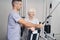 Manual therapist teaching aging lady exercise with cable machine