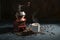 Manual wooden coffee grinder, white cup with the steaming hot drink and some roasted beans on a dark rustic background, copy space