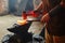 Manual work of a blacksmith in a blacksmith Shop. Hammer blows on the iron billet on the anvil. Forging sword blades is a retro