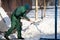 A manual worker scoops snow from the pavement and shovels it onto a pile next to it