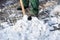 A manual worker scoops wet snow and ice on a shovel