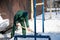 A manual worker scoops wet snow and ice on a shovel