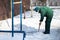 A manual worker scoops wet snow and ice on a shovel