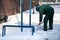 A manual worker scoops wet snow and ice on a shovel