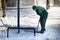 A manual worker scoops wet snow and ice on a shovel