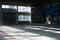 Manufacturing factory. Empty hangar building. Blue toned background. The production room with large windows and metal structures