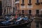 Many ampty gondolas and one gondolier, and tourists walk in the background in Venice, Italy