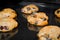 Many baked orange oatmeal raisin cookies on metal sheet: close up