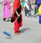 many barefoot women with colorful clothes sweep the paved road a