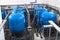 Many big blue water tanks inside wastewater treatment facility, industrial interior inside