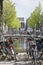 Many bikes are standing near the bridge in Amsterdam. Classic bridge over the canal in Amsterdam. The usual spring day