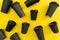 Many black takeaway coffee cups lay on yellow background,