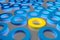 Many blue cylinder discs among which the yellow one stands out