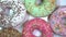 Many bright and colorful sprinkles donuts, macro shot, fast spinning on a rotating plate