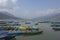 Many bright multicolored empty wooden boats on the Phewa lake on the background of a green mountain valley in the haze