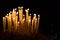 Many candles give warm yellow light in black background