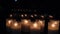 Many candles mysteriously burn in front of the window in complete darkness, blurred reflections and lights of lamps in the glass,