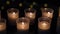 Many candles mysteriously burn in front of the window in complete darkness, blurred reflections and lights of lamps in the glass,