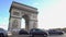 Many cars driving by Arc de Triomphe in sunlit Place Charles de Gaulle in Paris