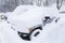 Many Cars on parking covered snow in snowbank after snowfall and blizzard in winter