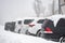 Many cars are parking during heavy snowing during winter