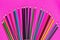 Many colored pencils lie on a pink background. Copy spase. The concept of back to school, the educational process, study at school